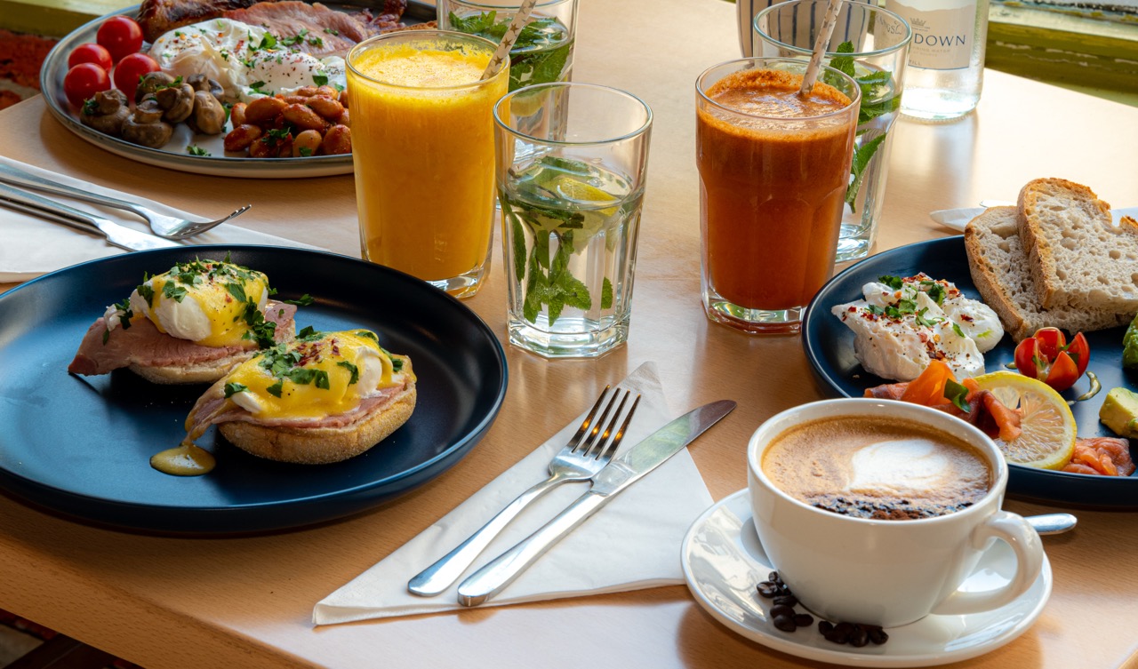 Brunch table spread with eggs benedict and drinks